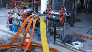 Four fire hoses connected to a fire department connection at a building still under construction.