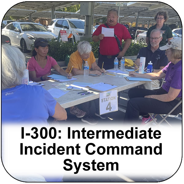 I-300 Intermediate Incident Command system. Seven people gathered around a table preparing paperwork. View course information